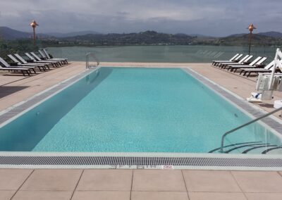 A pool with lounge chairs and a view of a lake.
