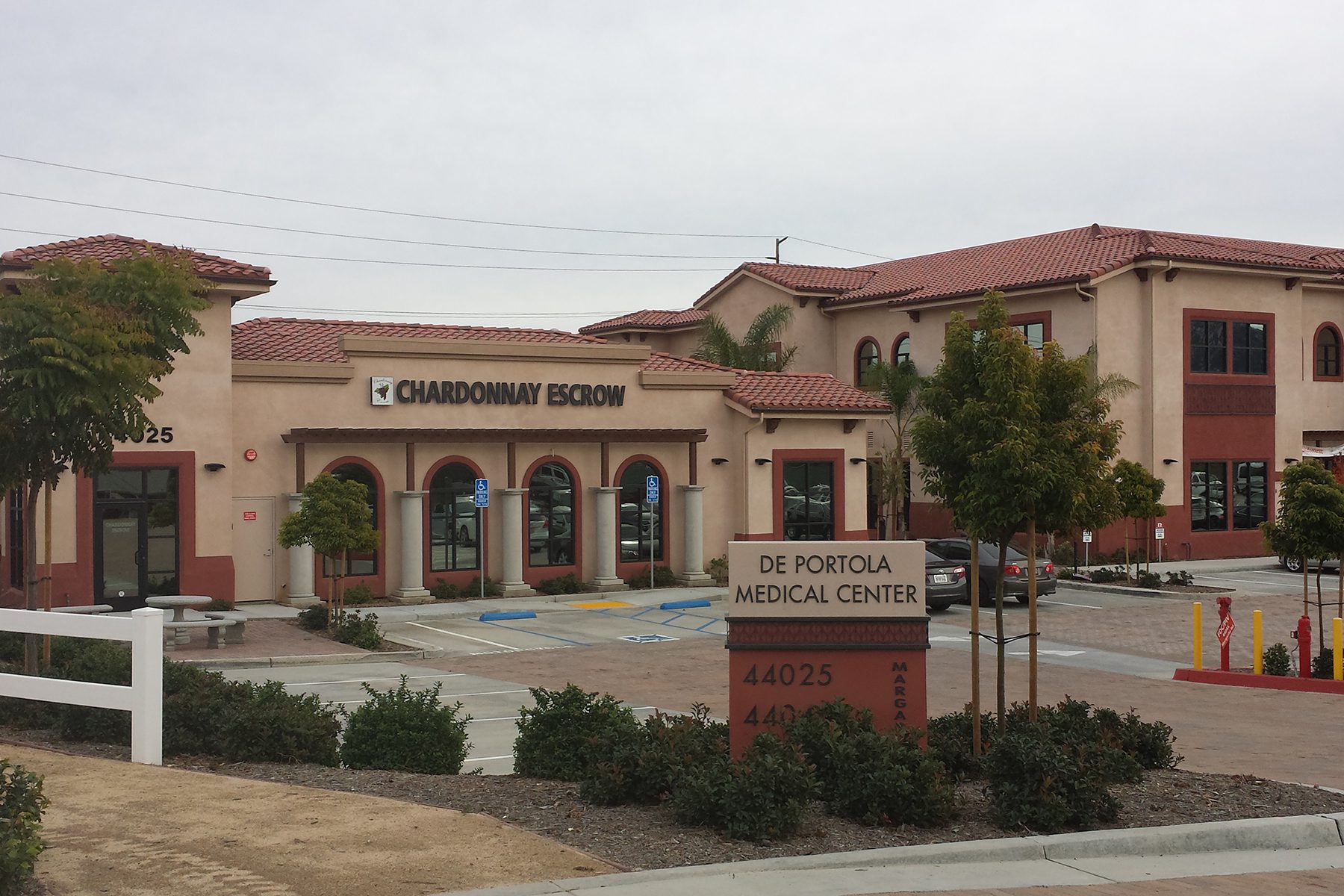 The front of a building with trees and bushes.